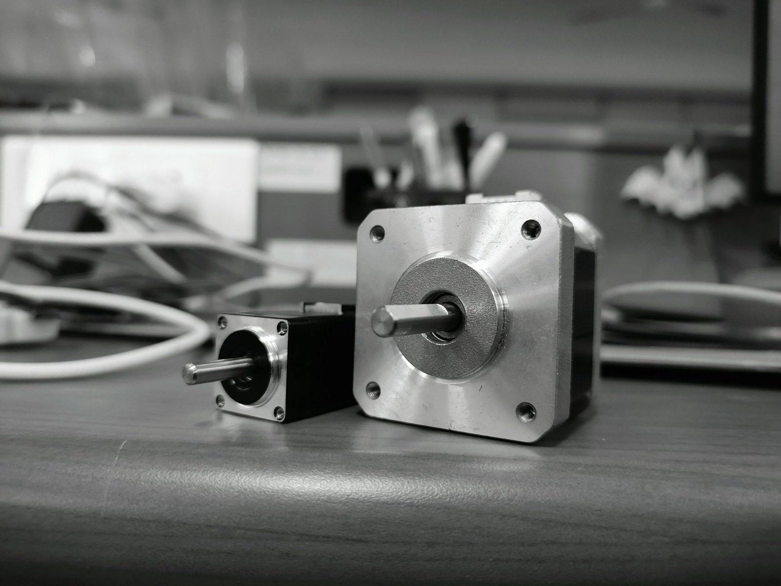 Close-up of two NEMA stepper motors on a desk, showing shaft detail and size difference.