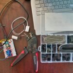 An organized electronics workbench with tools like a soldering iron, multimeter, and components for a hobbyist.