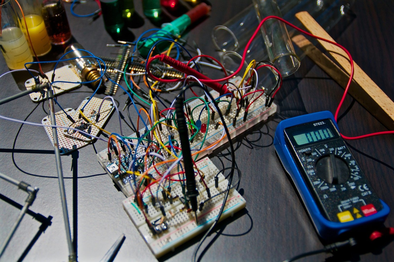 A dense breadboard project surrounded by colorful jumper wires and a digital multimeter, ready for voltage testing.