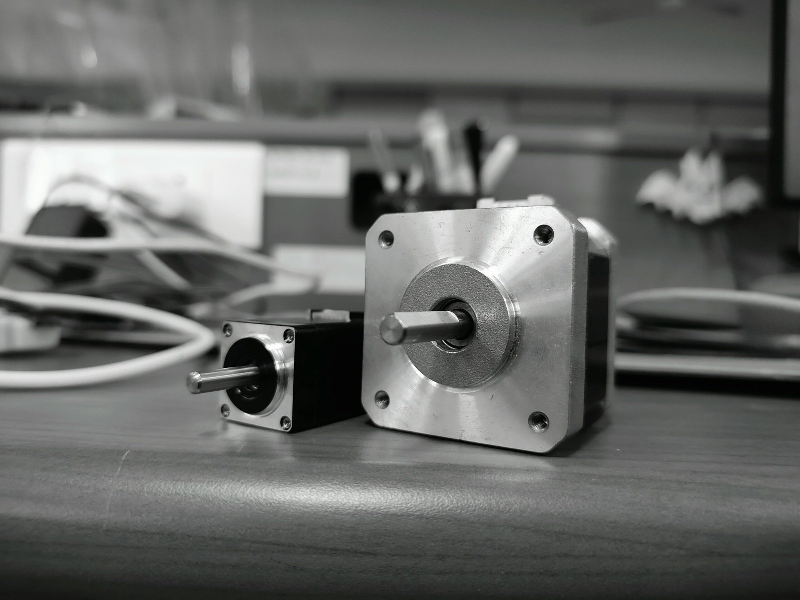 Close-up of two NEMA stepper motors on a desk, showing shaft detail and size difference.