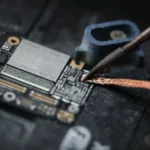 Close-up of a wire being soldered onto a circuit board with a soldering iron